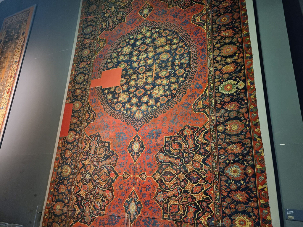 A 16th-century medallion Ushak carpet displayed at the Museum of Turkish and Islamic Arts in Istanbul, distinguished by its bold black, cream, and deep red color palette